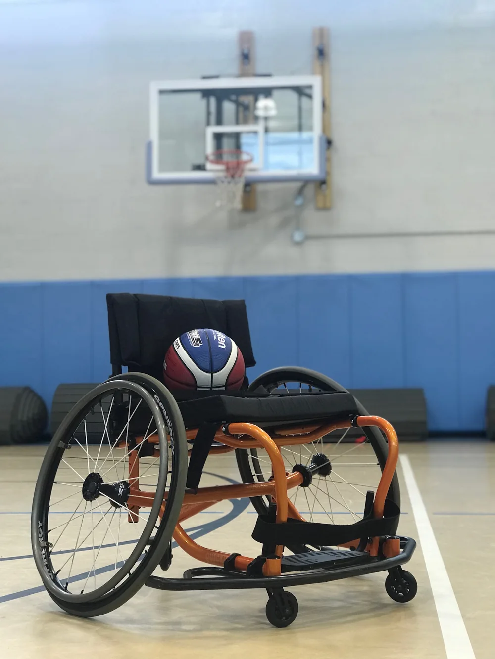 Een sportrolstoel met een basketbal op de zitting